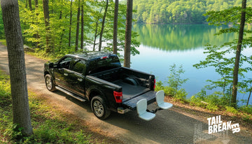 Black pickup truck with the Tailbreaker hitch-mounted dual seating system installed, tailgate open, parked on a dirt road abo