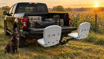 Tailbreaker hitch-mounted seating system on a pickup truck at a sunflower field edge with an open tailgate