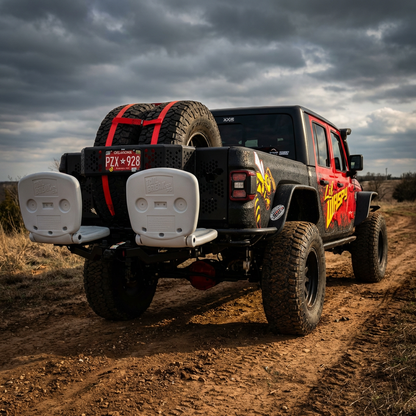Black Jeep Wrangler with red accents on a dirt road under a cloudy sky